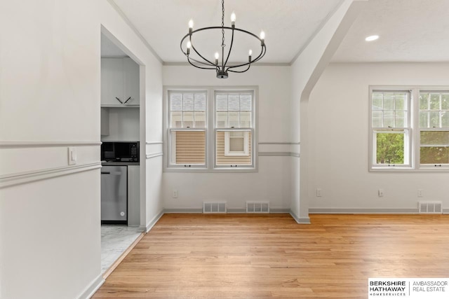 2035 N 50th St, Omaha, NE 68104 - unfurnished dining area featuring a chandelier, light wood-type flooring, arched walkways, baseboards, and recessed lighting