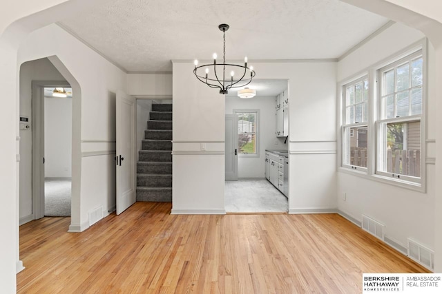 2035 N 50th St, Omaha, NE 68104 - unfurnished dining area featuring stairway, light wood finished floors, plenty of natural light, arched walkways, and crown molding