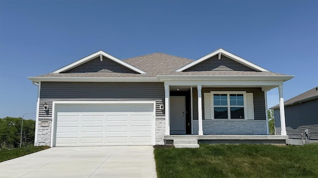 5503 N 188th St, Elkhorn, NE 68022 - view of front of home featuring stone siding, covered porch, concrete driveway, a garage, and roof with shingles