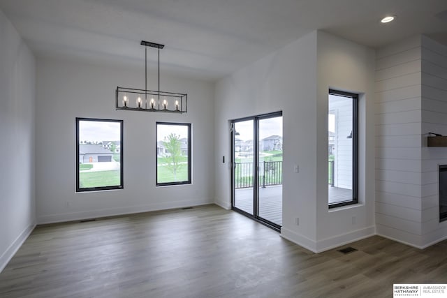 5717 S 200th Cir, Omaha, NE 68135 - unfurnished dining area featuring wood finished floors, a chandelier, baseboards, recessed lighting, and a fireplace