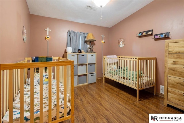 210 4th St, Ithaca, NE 68033 - bedroom with wood finished floors, baseboards, vaulted ceiling, and a crib