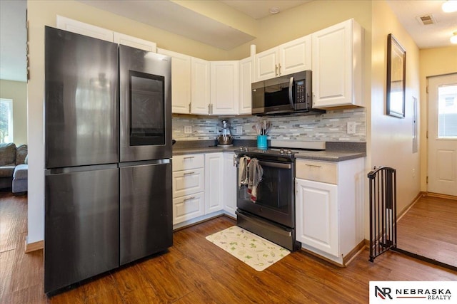 210 4th St, Ithaca, NE 68033 - kitchen with appliances with stainless steel finishes, dark countertops, white cabinetry, dark wood-style floors, and backsplash