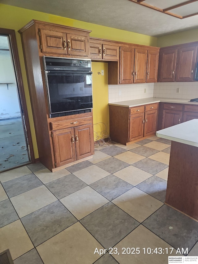 15911 S 234th St, Gretna, NE 68028 - kitchen with oven, backsplash, brown cabinetry, and light countertops