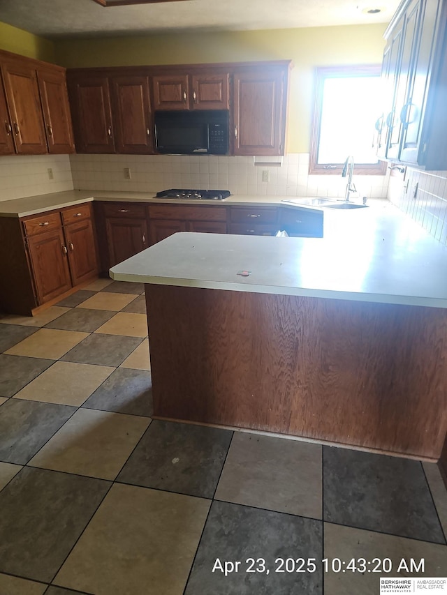 15911 S 234th St, Gretna, NE 68028 - kitchen with black microwave, stainless steel gas cooktop, decorative backsplash, light countertops, and a sink