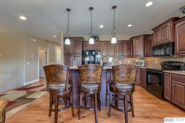 18855 Mason Plz, Omaha, NE 68022 - kitchen featuring black appliances, a kitchen island, light wood-style flooring, decorative backsplash, and a breakfast bar