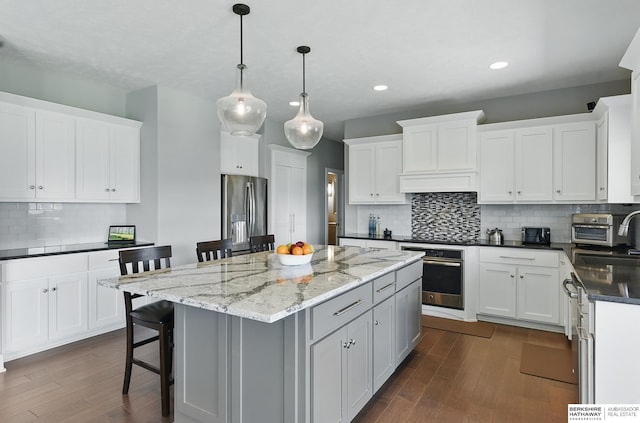20956 Pine Cir, Elkhorn, NE 68022 - kitchen featuring appliances with stainless steel finishes, a center island, decorative backsplash, dark wood-style floors, and recessed lighting