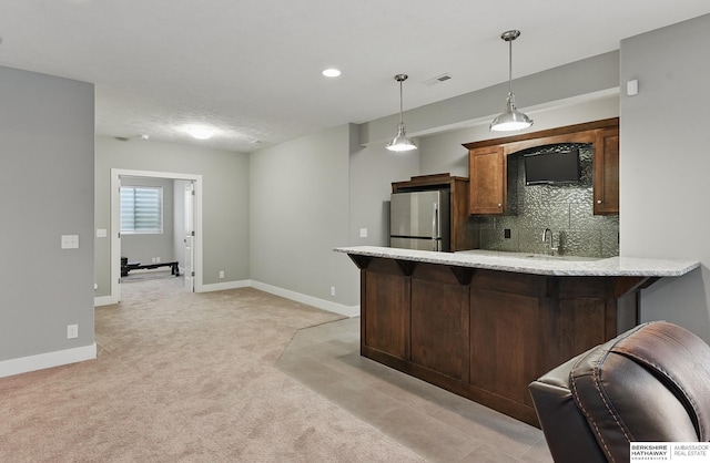 20956 Pine Cir, Elkhorn, NE 68022 - kitchen with freestanding refrigerator, light colored carpet, a peninsula, a breakfast bar, and decorative light fixtures