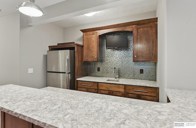 20956 Pine Cir, Elkhorn, NE 68022 - kitchen with freestanding refrigerator, decorative backsplash, light countertops, a sink, and hanging light fixtures