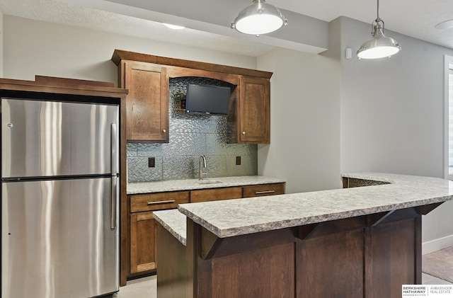20956 Pine Cir, Elkhorn, NE 68022 - kitchen with freestanding refrigerator, a sink, light countertops, decorative backsplash, and hanging light fixtures
