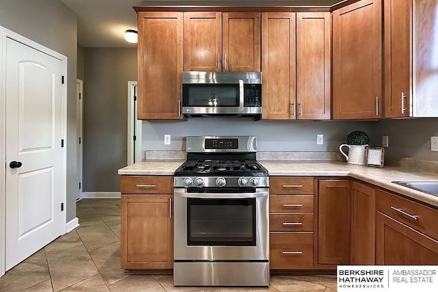 18914 C St, Omaha, NE 68130 - kitchen with stainless steel appliances, brown cabinets, light tile patterned floors, and light countertops