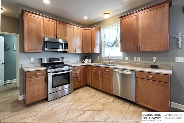 18914 C St, Omaha, NE 68130 - kitchen featuring stainless steel appliances, a sink, light countertops, recessed lighting, and brown cabinetry
