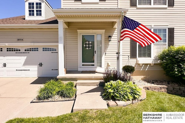 18914 C St, Omaha, NE 68130 - view of exterior entry with driveway, a garage, and a shingled roof
