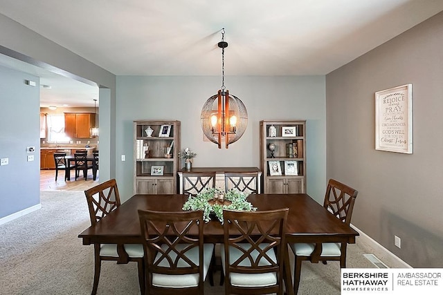 18914 C St, Omaha, NE 68130 - dining room featuring a chandelier, light carpet, and baseboards