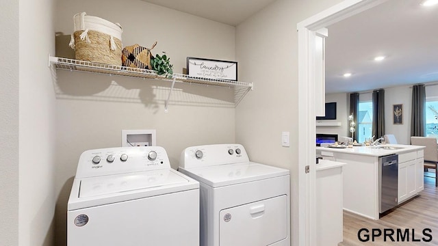 17063 Reynolds St, Bennington, NE 68007 - laundry area featuring independent washer and dryer, light wood-style flooring, recessed lighting, and a glass covered fireplace