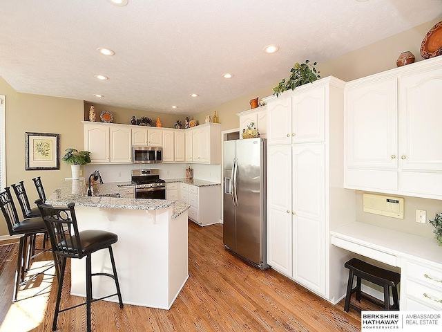 5103 N 140th St, Omaha, NE 68164 - kitchen featuring appliances with stainless steel finishes, a peninsula, recessed lighting, a breakfast bar, and light wood-style floors