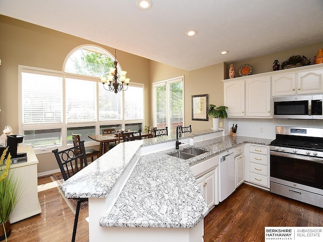 5103 N 140th St, Omaha, NE 68164 - kitchen featuring appliances with stainless steel finishes, a peninsula, a sink, a chandelier, and dark wood finished floors
