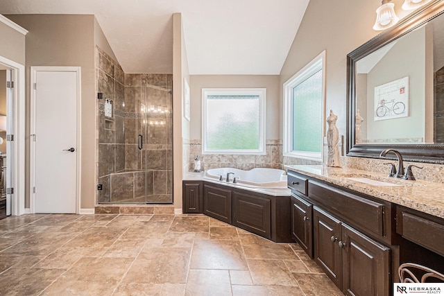 2221 S 181st Cir, Omaha, NE 68130 - bathroom featuring vanity, a shower stall, a bath, vaulted ceiling, and stone tile flooring