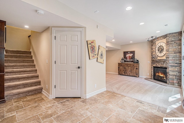 2221 S 181st Cir, Omaha, NE 68130 - unfurnished living room featuring stairway, stone tile flooring, a stone fireplace, recessed lighting, and light colored carpet