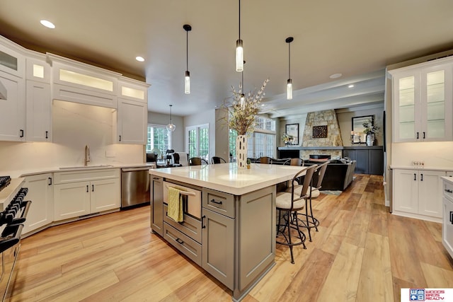 6602 Pheasant Run Pl, Lincoln, NE 68516 - kitchen featuring stainless steel dishwasher, a sink, a breakfast bar area, light wood-style floors, and pendant lighting