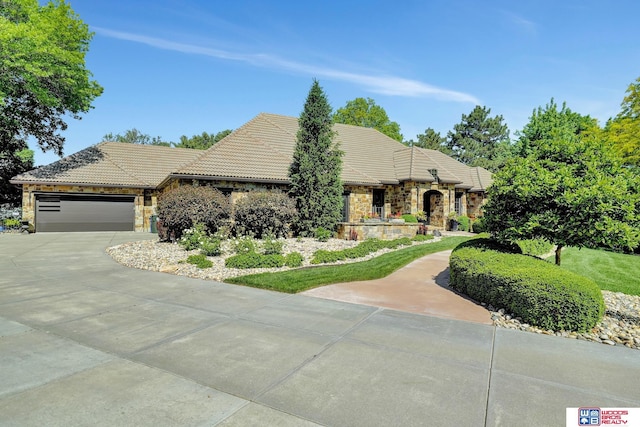 6602 Pheasant Run Pl, Lincoln, NE 68516 - view of front of home featuring stone siding, an attached garage, concrete driveway, and a tile roof