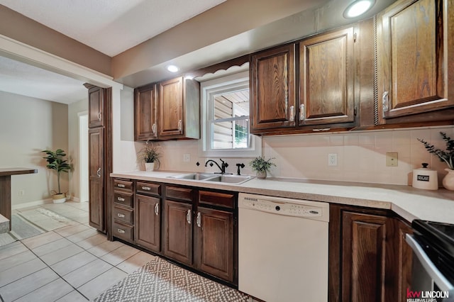 430 N 86th St, Lincoln, NE 68505 - kitchen featuring white dishwasher, a sink, light countertops, decorative backsplash, and light tile patterned flooring