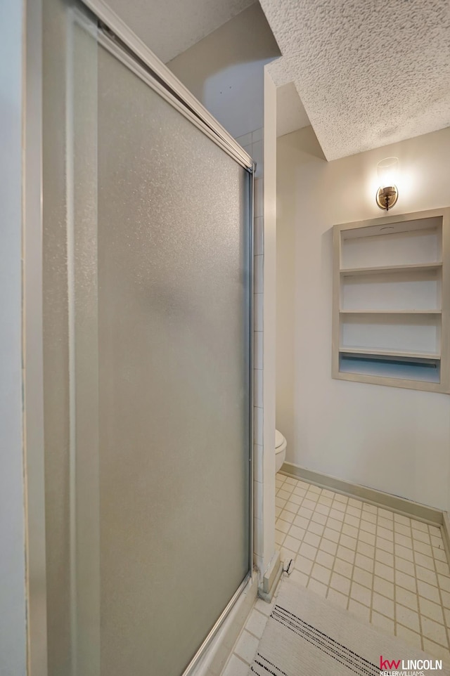 430 N 86th St, Lincoln, NE 68505 - bathroom featuring a stall shower, baseboards, toilet, tile patterned flooring, and a textured ceiling
