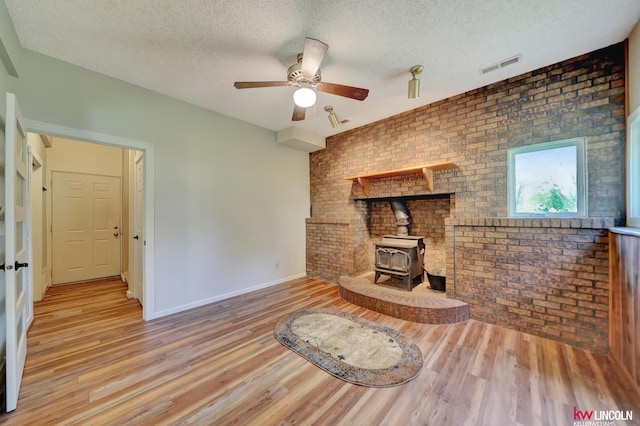 430 N 86th St, Lincoln, NE 68505 - unfurnished living room featuring brick wall, a wood stove, wood finished floors, a textured ceiling, and baseboards