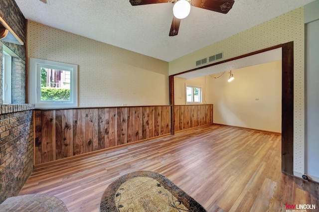 430 N 86th St, Lincoln, NE 68505 - empty room featuring wood finished floors, a textured ceiling, wallpapered walls, a wainscoted wall, and a ceiling fan