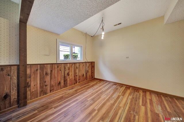 430 N 86th St, Lincoln, NE 68505 - empty room featuring wood finished floors, a textured ceiling, wood walls, and baseboards