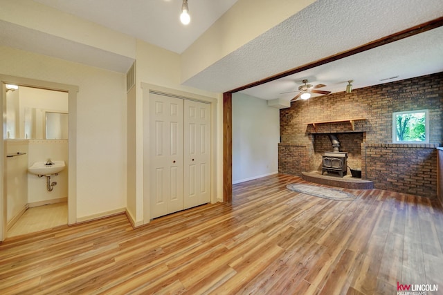430 N 86th St, Lincoln, NE 68505 - unfurnished living room with a wood stove, wood finished floors, brick wall, baseboards, and ceiling fan