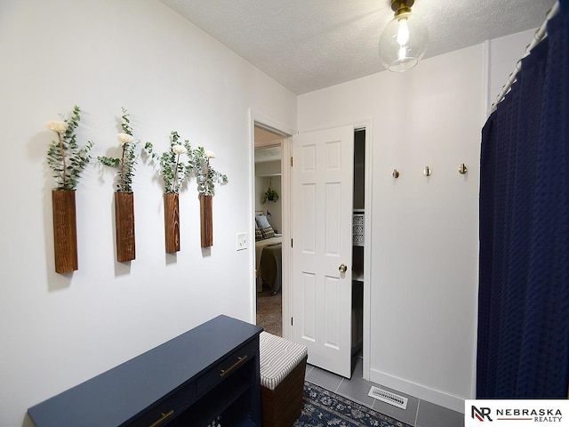 4219 Browning St, Lincoln, NE 68516 - hall featuring dark tile patterned flooring, a textured ceiling, and baseboards
