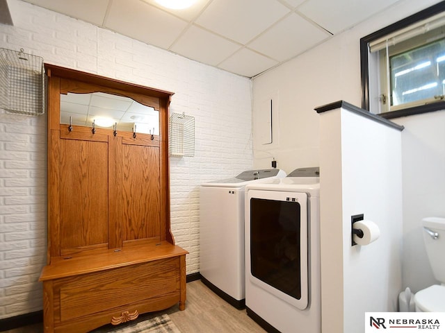 4219 Browning St, Lincoln, NE 68516 - laundry room with washer and clothes dryer, light wood-style floors, and brick wall