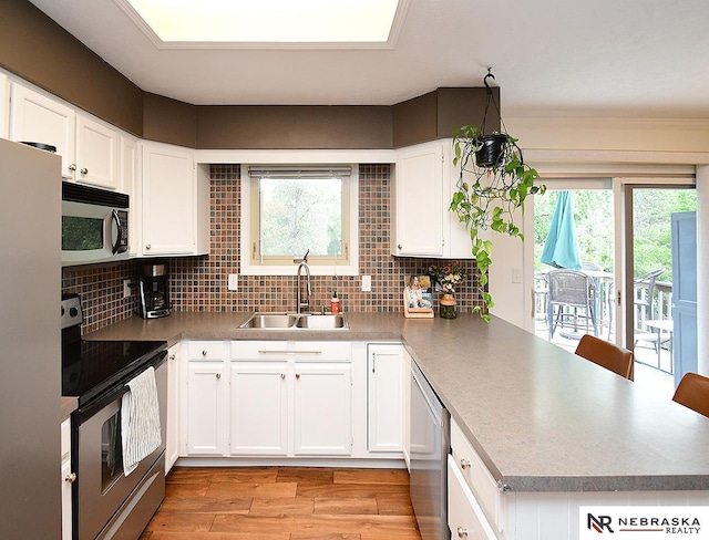 4219 Browning St, Lincoln, NE 68516 - kitchen featuring stainless steel appliances, a sink, a peninsula, light wood finished floors, and tasteful backsplash