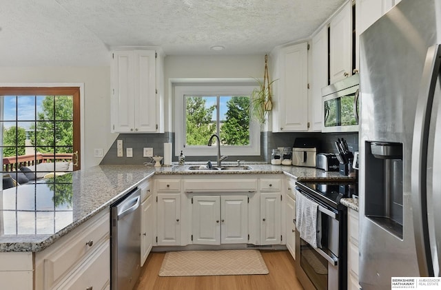 4019 N 147th St, Omaha, NE 68116 - kitchen with stainless steel appliances, a sink, a peninsula, plenty of natural light, and a textured ceiling