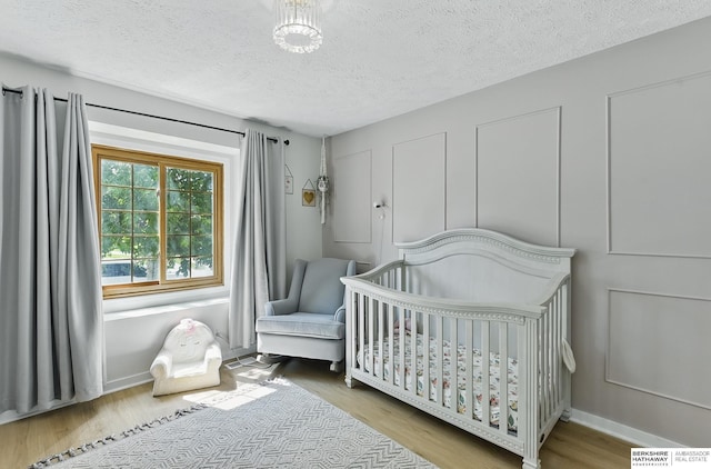 4019 N 147th St, Omaha, NE 68116 - bedroom with wood finished floors, a textured ceiling, a nursery area, and baseboards