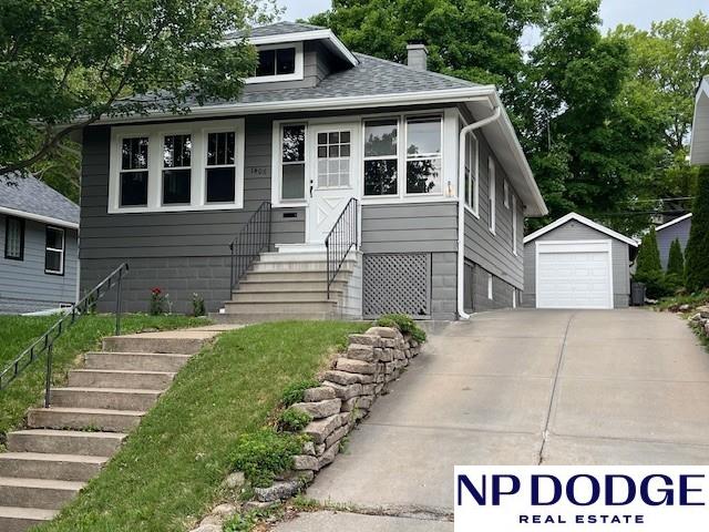 1406 S 55th St, Omaha, NE 68106 - bungalow-style house with a chimney, an outdoor structure, a garage, roof with shingles, and stairs
