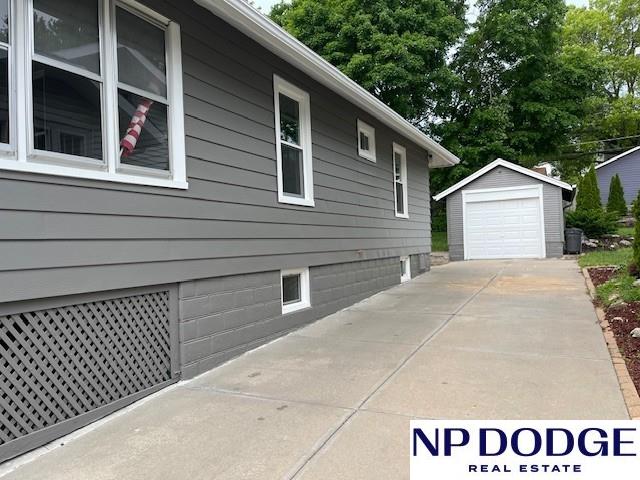 1406 S 55th St, Omaha, NE 68106 - view of home's exterior with an outdoor structure, a detached garage, and concrete driveway