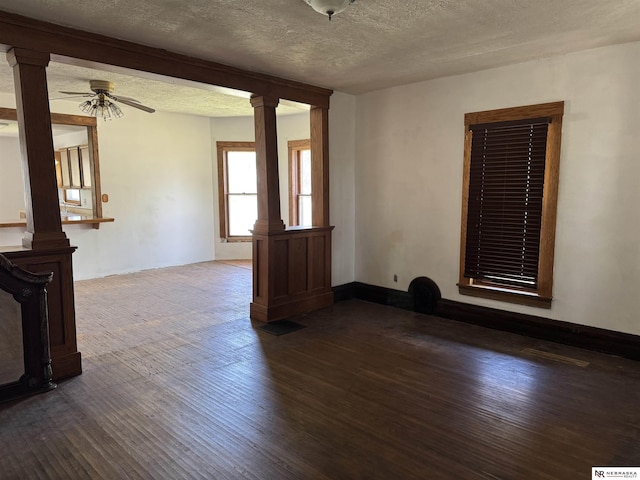 204 E York Ave, Dewitt, NE 68341 - unfurnished room featuring a textured ceiling, dark wood finished floors, ceiling fan, and ornate columns