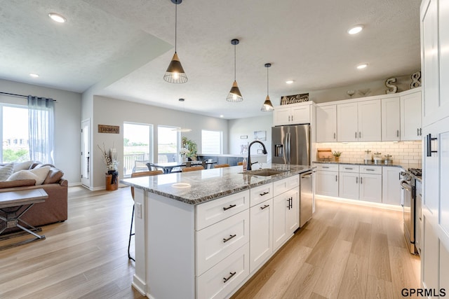 18403 Greenleaf St, Omaha, NE 68136 - kitchen featuring stainless steel appliances, a sink, light wood-style floors, recessed lighting, and light stone countertops