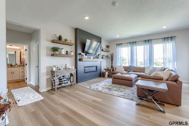 18403 Greenleaf St, Omaha, NE 68136 - living area featuring light wood-type flooring, a large fireplace, recessed lighting, a textured ceiling, and baseboards