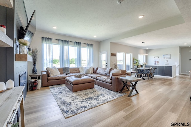 18403 Greenleaf St, Omaha, NE 68136 - living area featuring light wood finished floors, a textured ceiling, a glass covered fireplace, and recessed lighting