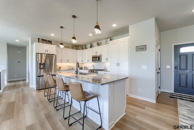 18403 Greenleaf St, Omaha, NE 68136 - kitchen with stainless steel appliances, white cabinetry, light wood-type flooring, decorative backsplash, and light stone counters