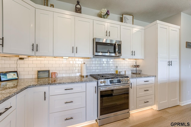 18403 Greenleaf St, Omaha, NE 68136 - kitchen with appliances with stainless steel finishes, light wood finished floors, white cabinetry, backsplash, and a textured ceiling