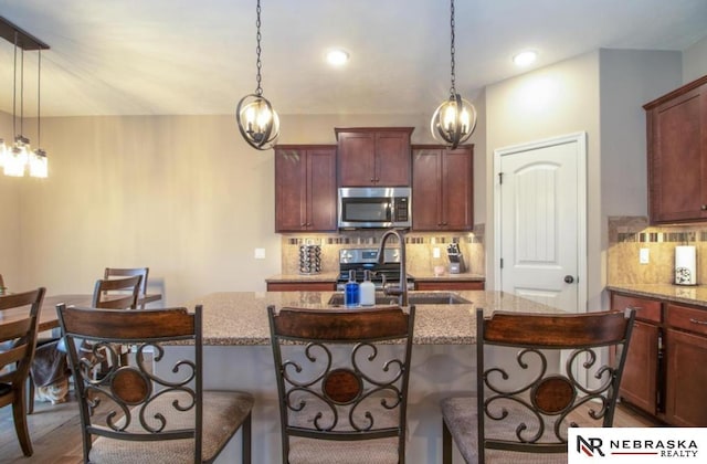 10425 S 110th St, Papillion, NE 68046 - kitchen featuring appliances with stainless steel finishes, backsplash, a kitchen bar, and hanging light fixtures