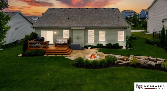 10425 S 110th St, Papillion, NE 68046 - back of property at dusk featuring a wooden deck, an outdoor living space with a fire pit, a patio area, and roof with shingles