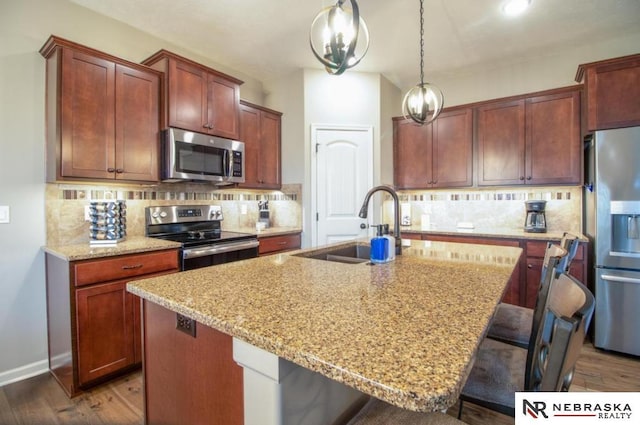 10425 S 110th St, Papillion, NE 68046 - kitchen featuring appliances with stainless steel finishes, a sink, a kitchen breakfast bar, tasteful backsplash, and light stone countertops