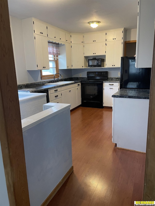 608 N 16th St, Nebraska City, NE 68410 - kitchen featuring black appliances, a sink, dark wood-style floors, dark countertops, and white cabinets