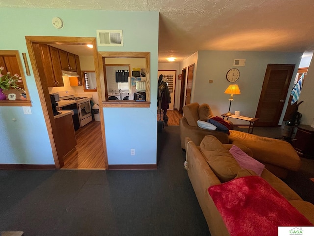 5427 W Hughes St, Lincoln, NE 68524 - kitchen with white gas stove, under cabinet range hood, baseboards, brown cabinets, and a textured ceiling
