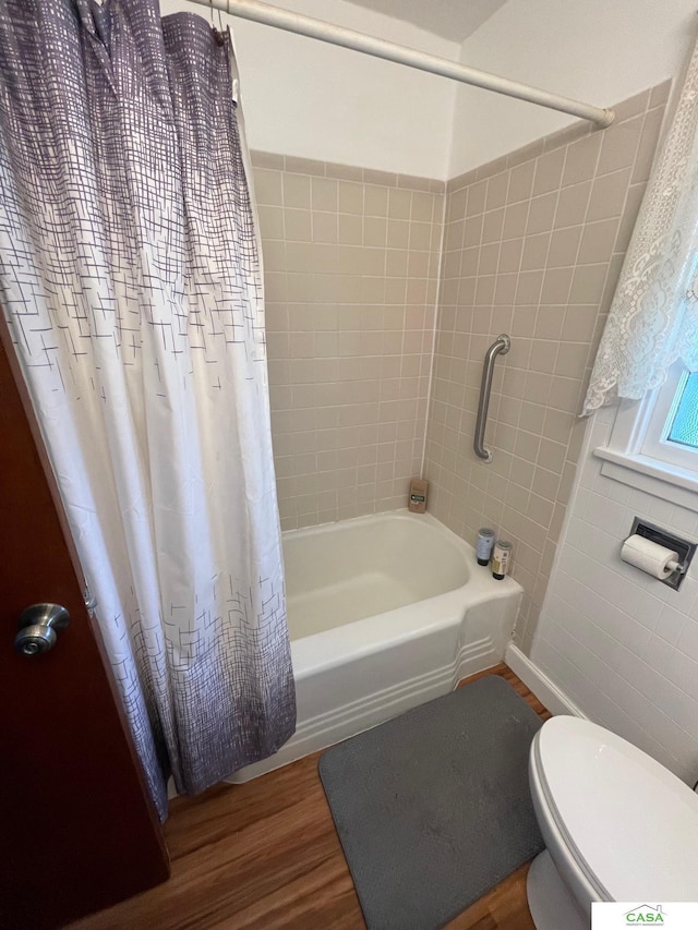 5427 W Hughes St, Lincoln, NE 68524 - bathroom featuring tile walls, wood finished floors, shower / bath combination with curtain, and toilet