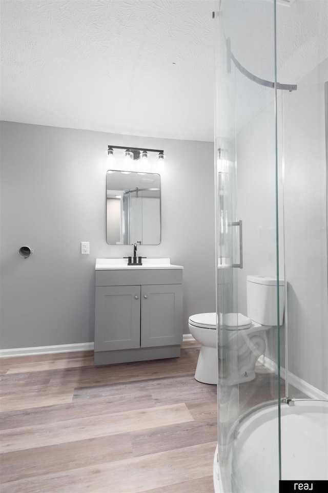 1204 S 27th St, Omaha, NE 68105 - bathroom with toilet, vanity, a stall shower, wood finished floors, and a textured ceiling